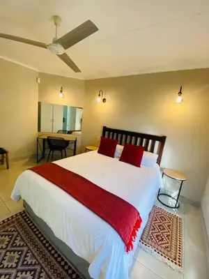a bedroom with a large white bed with red pillows at Shingalana Guest Lodge in Hazyview