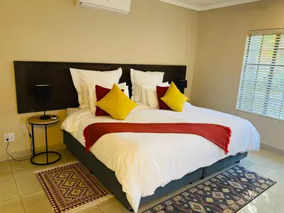 a bedroom with a large bed with yellow and red pillows at Shingalana Guest Lodge in Hazyview