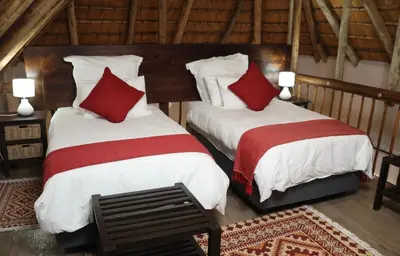 two beds with red and white pillows in a room at Shingalana Guest Lodge in Hazyview
