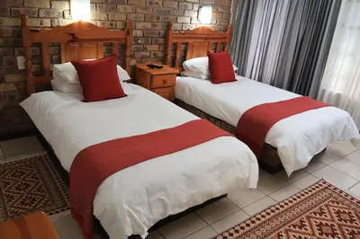 two beds with red and white sheets in a room at Shingalana Guest Lodge in Hazyview