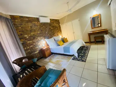 a bedroom with a bed and a brick wall at Shingalana Guest Lodge in Hazyview