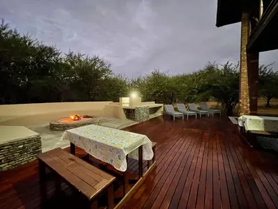 a wooden deck with a table and a fire pit at Nghala Self-catering Holiday Home in Marloth Park