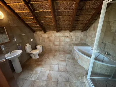 a bathroom with a tub and a toilet and a sink at Nghala Self-catering Holiday Home in Marloth Park