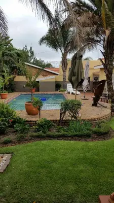 a backyard with a swimming pool and palm trees at Kalahari Guest House in Witbank