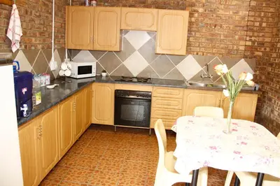 a kitchen with wooden cabinets and a table with a vase at Kalahari Guest House in Witbank