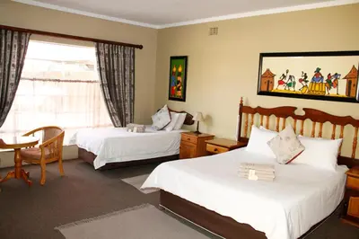 a hotel room with two beds and a table at Kalahari Guest House in Witbank