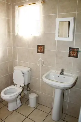 a bathroom with a toilet and a sink at Kalahari Guest House in Witbank