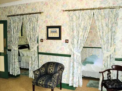a bedroom with a bed and a chair and curtains at A Pilgrims Rest Guest House in Graskop in Graskop