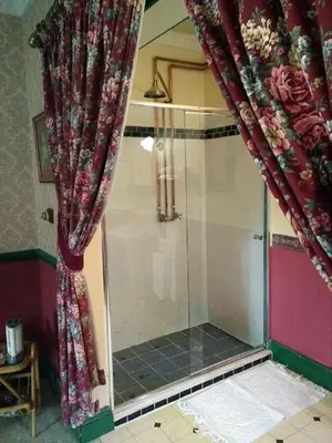 a shower with a glass door and red curtains at A Pilgrims Rest Guest House in Graskop in Graskop