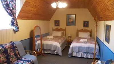 a bedroom with two beds and a chair in a room at A Pilgrims Rest Guest House in Graskop in Graskop