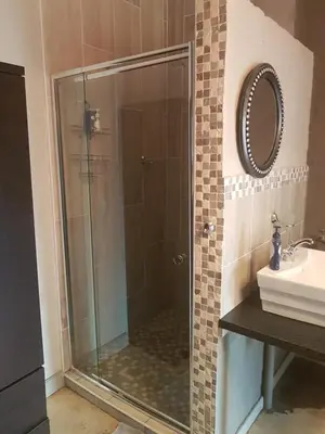 a glass shower in a bathroom with a sink at Africas Eden Guesthouse in Naboomspruit