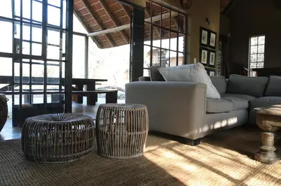 a living room with a couch and two stools at Villa ZaZu in Marloth Park