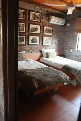 two beds in a room with pictures on the wall at Villa ZaZu in Marloth Park