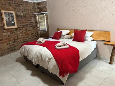 a bedroom with a large bed with a red blanket at Witgatboom Boskamp in Naboomspruit