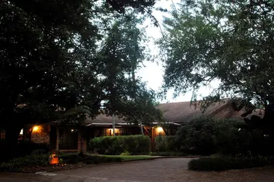 a house at night with a driveway in front of it at Tamboti House in Malelane