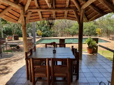 a wooden table and chairs under a wooden pergola at Tamboti House in Malelane