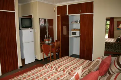 a room with a bed and a kitchen with a table at Tamboti House in Malelane