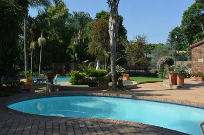 a large swimming pool in a yard with trees at Cornerstone Guest Lodge in Pretoria