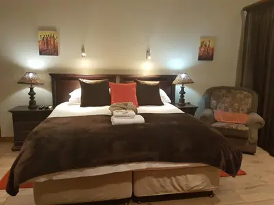 a bedroom with a large bed and a chair at Cornerstone Guest Lodge in Pretoria