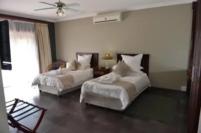 a bedroom with two beds and a ceiling fan at Cornerstone Guest Lodge in Pretoria