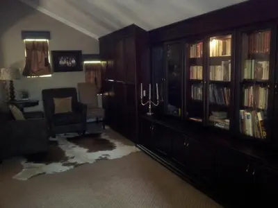 a living room with a book shelf and a chair at Cornerstone Guest Lodge in Pretoria