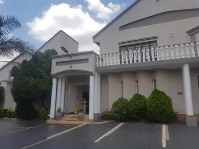 a large white building with a parking lot at Cornerstone Guest Lodge in Pretoria