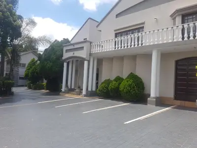 a large white building with a parking lot at Cornerstone Guest Lodge in Pretoria