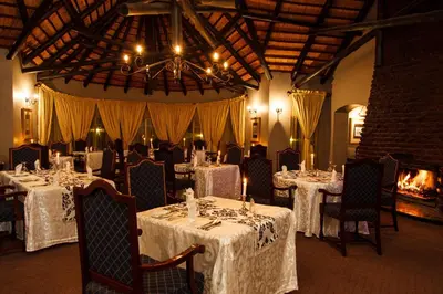 a dining room with tables and chairs and a fireplace at Mount Sheba Rainforest Hotel - Mountain Spring Water in Pilgrimʼs Rest