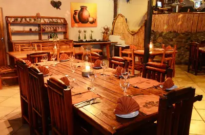 a large wooden table in a restaurant with chairs at Pezulu Tree House Lodge in Hoedspruit