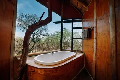 a large bath tub in a room with a window at Pezulu Tree House Lodge in Hoedspruit