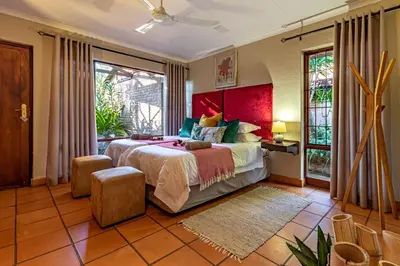 a bedroom with a large bed with a red wall at Ulwazi Rock Lodge in Hazyview