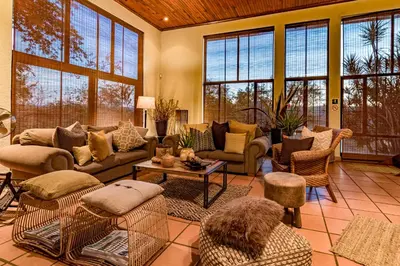 a living room with a couch and chairs and windows at Ulwazi Rock Lodge in Hazyview