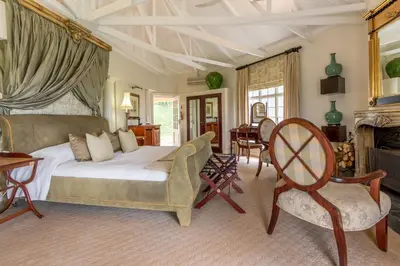 a bedroom with a bed and chairs and a fireplace at Serra Azul Lodge in Hazyview