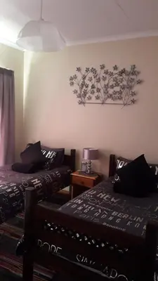 a bedroom with two beds and a painting on the wall at Pride Rock Accommodation in Middelburg