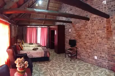 a bedroom with a bed and a brick wall at Pride Rock Accommodation in Middelburg