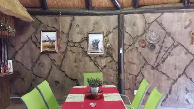 a table and chairs in a room with a stone wall at Pride Rock Accommodation in Middelburg