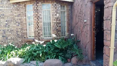 a brick building with windows and flowers in a garden at Pride Rock Accommodation in Middelburg