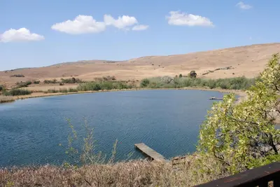 a large lake with a dock in the middle at Valley of the Rainbow Fly Fishing Estate in Dullstroom