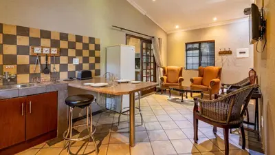 a kitchen with a table and chairs in a room at Paradise Creek Lodge in Malelane