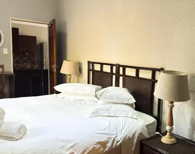 a bedroom with a bed with white sheets and pillows at Paradise Creek Lodge in Malelane