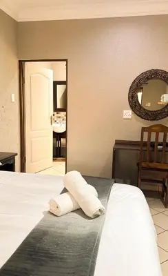 a bedroom with a bed with a mirror on the wall at Paradise Creek Lodge in Malelane