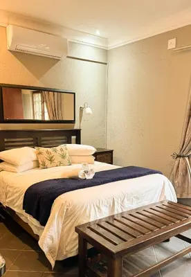 a hotel room with a bed and a bench at Paradise Creek Lodge in Malelane