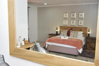 a bedroom with a bed and a large mirror at Cuckoos Nest Guest House in Louis Trichardt