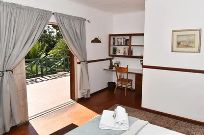 a bedroom with a door open to a balcony at Cuckoos Nest Guest House in Louis Trichardt