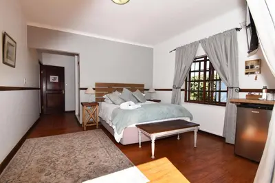 a bedroom with a bed and a large window at Cuckoos Nest Guest House in Louis Trichardt