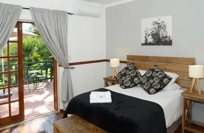 a bedroom with a bed and a balcony at Cuckoos Nest Guest House in Louis Trichardt
