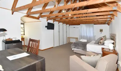a bedroom with a bed and a desk in a room at Cuckoos Nest Guest House in Louis Trichardt