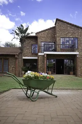 a bench with flowers in it in front of a building at Peter's Guesthouse in Pretoria