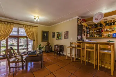 a living room with a bar and some chairs at Peter's Guesthouse in Pretoria