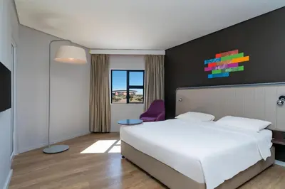 a bedroom with a white bed and a purple chair at Park Inn by Radisson Polokwane in Polokwane
